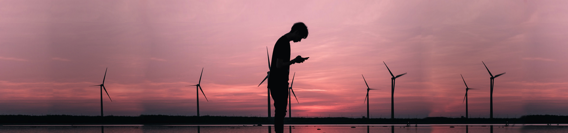 Boy looking at phone wind turbines in background